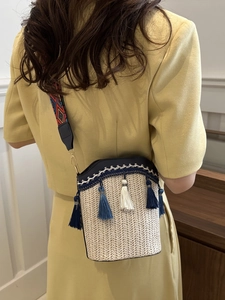 Detail of woven bucket bag featuring blue fringe tassels and ethnic style wide shoulder strap