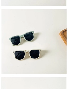 Flat lay of foldable mint green and off-white kids sunglasses with dark square lenses