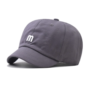 Detail of grey short brim baseball cap with white m letter embroidery in cotton twill