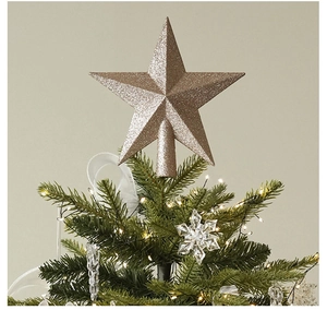 Close-up of champagne gold glittery star tree topper on a lush green Christmas tree