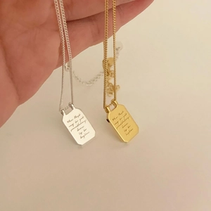 Detail of engraved inspirational quote on gold and silver rectangular necklace pendants
