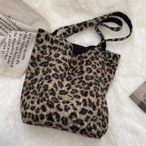 Detail of leopard print plush tote bag featuring a golden logo plate and fuzzy texture