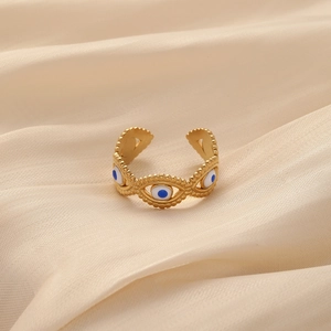 Detail of adjustable gold ring with blue evil eye charms on champagne satin