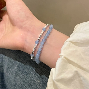 Détail de deux bracelets en perles d'aigue-marine bleu clair sur le poignet d'un modèle