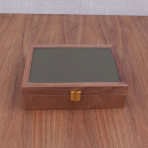 Détail d'un coffret de montre en bois vintage avec fermoir en métal doré et panneau noir mat