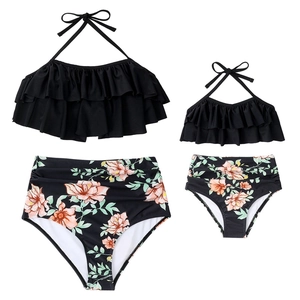 Flat lay of matching mother and daughter two-piece swimwear with floral high-waisted bottoms
