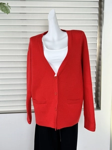 Detailed close-up of chunky red knit cardigan featuring V-neckline and three button closure