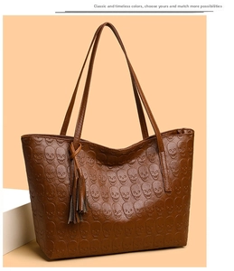 Detailed view of the brown leather tote bag with skull embossing and tassel charm
