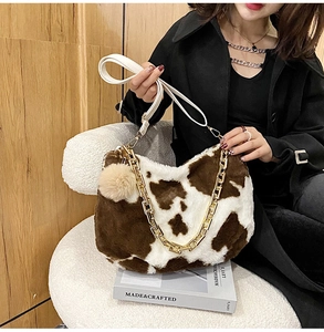 Detailed shot of cow print plush tote bag with gold chain and white leather strap