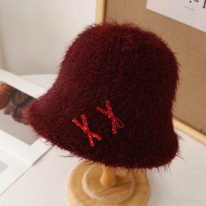 Vista detallada de un gorro de pescador granate peludo con adornos de lazos rojos.