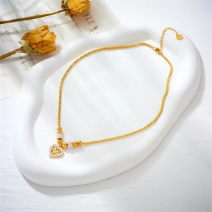 Gold tree of life heart necklace with sparkling zircon beads on vintage white tray