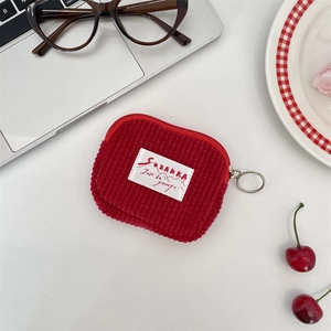 Detail of red corduroy mini storage pouch with zipper closure on white office desk