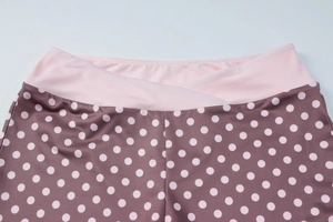 Détail de la taille croisée en V sur un pantalon marron à pois avec coutures roses