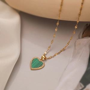 Macro detail of a gold-plated heart pendant necklace with green malachite and small crystals