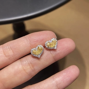Gros plan de boucles d'oreilles cœur en zircone jaune avec sertissage micro-pavé à la main