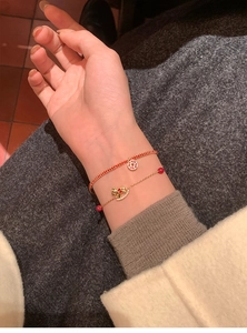 Detail of red cord and 18k gold-plated chain bracelet set with horse charm and zircon