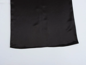 Detail view of smooth black satin hemline with fine stitching on an elegant evening dress