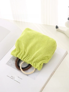 Close-up of grass green corduroy makeup pouch featuring a striped texture and woven handle