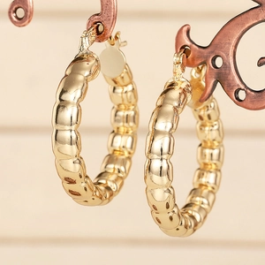 Goldene geknotete Creolen mit strukturierter Segmentierung auf Vintage-Metallständer
