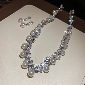 Elegant pearl and diamond jewelry set featuring necklace and earrings on white leather