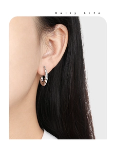 Detail view of silver twisted hoop earrings showing the elegant metallic texture on model