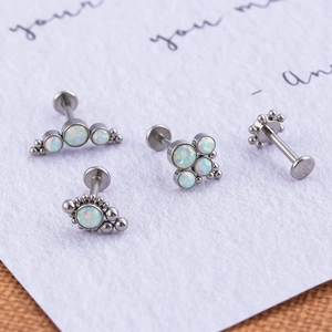 Detail of silver stainless steel lip studs featuring white opal clusters on a white card