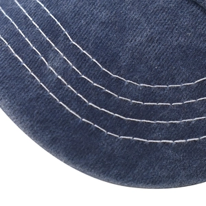 Détail macro du bord de casquette en coton bleu marine avec quatre rangées de coutures blanches