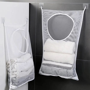 White mesh hanging laundry storage bag with towels and round opening on bathroom wall