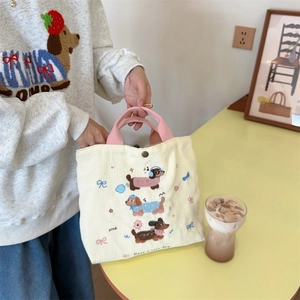 Dettaglio borsa tote in velluto a coste beige con ricami bassotto e manici rosa