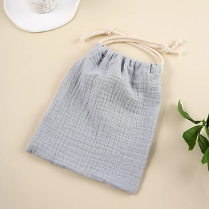 Flat lay of gray muslin cotton drawstring storage bag with textured fabric and cream rope