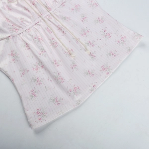 Détail d'un caraco à imprimé fleuri rose avec cordon de serrage et coutures fines