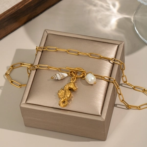 Detail of 18K gold seahorse, shell and pearl charms on an OT toggle chain necklace