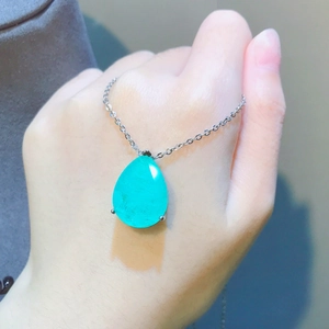 Macro view of a pear-cut emerald-colored pendant featuring a three-prong silver setting