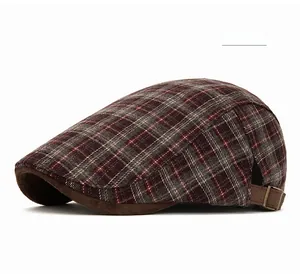 Dettaglio cappello newsboy scozzese rosso scuro con fibbia in metallo e tesa scamosciata