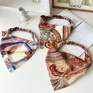 Flat lay of vintage paisley silk bandanas with elastic bands on a white surface