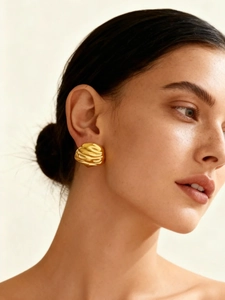Macro shot of 18k gold-plated geometric wrinkled earrings on a model's ear