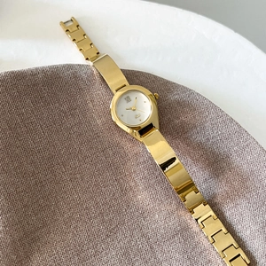 Elegant gold bangle watch for women featuring a white dial and roman numerals