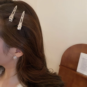 Détail de barrettes argentées et boucles d'oreilles boutons beiges portées par un mannequin