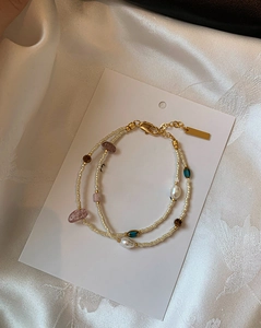 Detail of double-layer gold plated bracelet with freshwater pearls and colored crystals