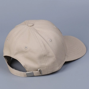 Détail de la boucle en métal ajustable sur une casquette de baseball en coton beige