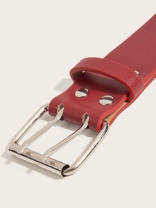 Detail view of the silver metal buckle and eyelet design on a red punk style leather belt