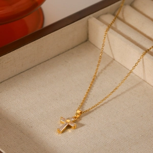 Macro shot of 18K gold plated cross pendant with cubic zirconia inlay in a jewelry box