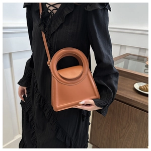Close-up of caramel leather handbag featuring a unique large circular cutout handle detail