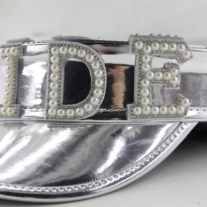 Detailed view of silver party hat featuring intricate pearl and rhinestone 3D letter embellishments