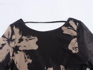 Detail van een zwarte transparante mesh top met bruine bloemenprint en een ronde halslijn