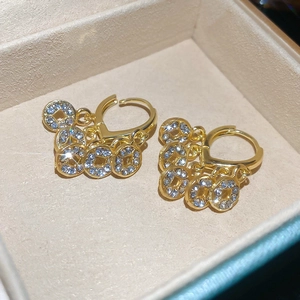 Detail von Goldmünzen-Ohrringen mit funkelnden Diamanten auf beiger Schmuckschatulle