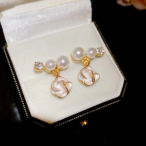 Détail macro de boucles d'oreilles fleurs dorées avec perles et strass dans une boîte à bijoux