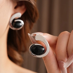 Close-up of number 6 shaped silver earring with a black oval gemstone on a model