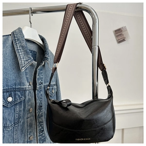 Dettaglio borsa a mezzaluna nera con tracolla geometrica e scritta dorata fashion