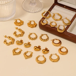 Collection of minimalist gold plated hoop earrings and textured studs on a velvet jewelry box
